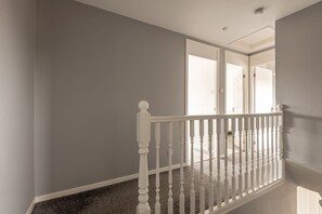 A staircase with white balusters and a carpeted landing.