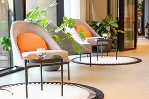 Relax in the stylish lobby, surrounded by lush greenery and a glass wall offering a view of the outside.