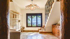 A spacious room with a staircase, a large window with a view, and a unique ceiling light fixture.