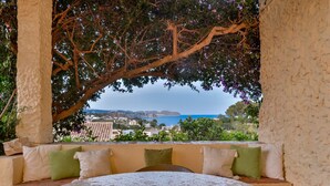 A terrace with a view of the sea, a table, and a bench with cushions.