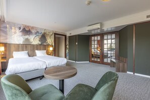 Relax in a stylish room with a large bed, round table, and comfortable chairs.