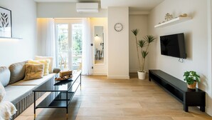 Una sala de estar moderna con sofá, mesa de centro, televisor y plantas.