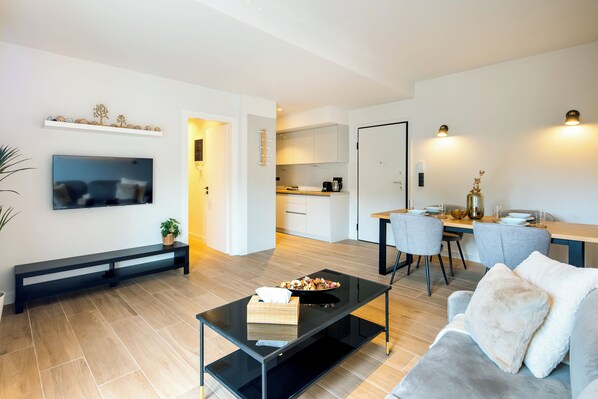 A modern living room with a flat-screen TV, a glass coffee table, and a grey sofa. - Nova 1-Bedroom Apartment in Athens (Athens)