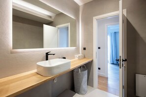 A modern bathroom with a large mirror, a white sink, and a wooden countertop. - Nova 1-Bedroom Apartment in Athens (Athens)