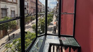 A view through a window with a red wall, showcasing a street with buildings and trees.