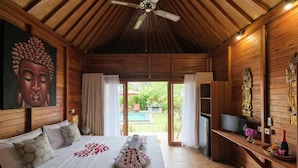 Un dormitorio amplio con una cama grande, techo de madera y vistas a una piscina.