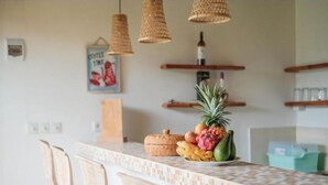 Una cocina con salpicadero de azulejos, sillas de madera y un frutero sobre la encimera.