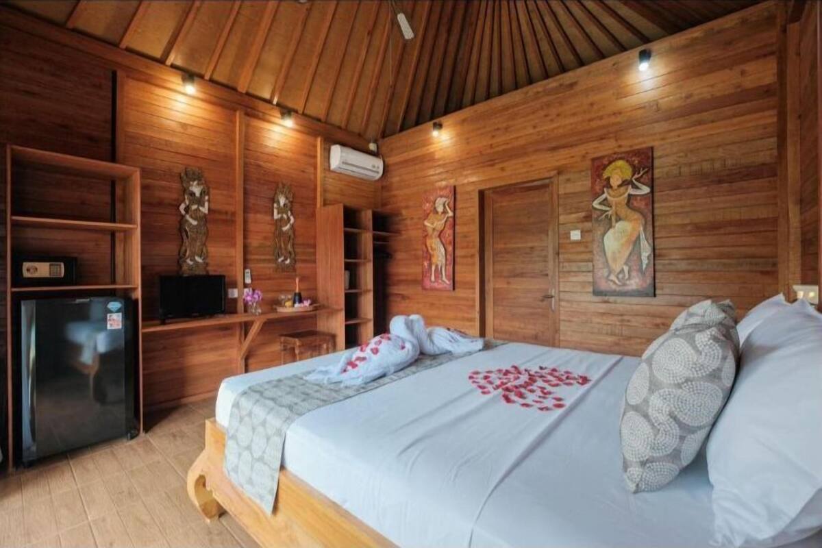 Quarto de cabana de madeira com cama, televisão e frigorífico.