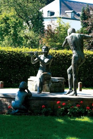 Stunning bronze statues come to life in this serene sculpture garden, surrounded by lush greenery and vibrant flowers.