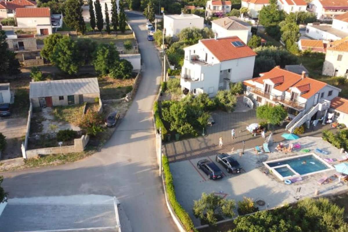 Vista aérea de una zona residencial con casas, piscina y aparcamiento.