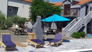 A pool area with lounge chairs, a covered seating area, and a staircase leading to a balcony. - Apartments Franica With Heated Pool and Hot-tub (Privlaka)