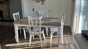 Ein Essbereich mit einem Holztisch, weißen Stühlen, einer Kristallleuchtre und einer Steinwand mit Pflanzen.