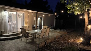 Eine Terrasse im Freien mit Tisch und Stühlen, einer überdachten Sitzgelegenheit und Lichterketten.
