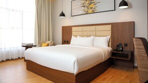 A modern hotel room with a large bed, wooden headboard, bedside tables, a telephone, and a painting on the wall. - Palm Core Hotel Al Rabwah (Riyadh)