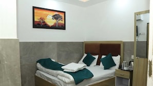 Un dormitorio ordenado con cama, almohadas, una mesita de noche y un cuadro en la pared.