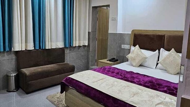 Un dormitorio moderno con cama, sofá, ventilador de techo y cortinas.