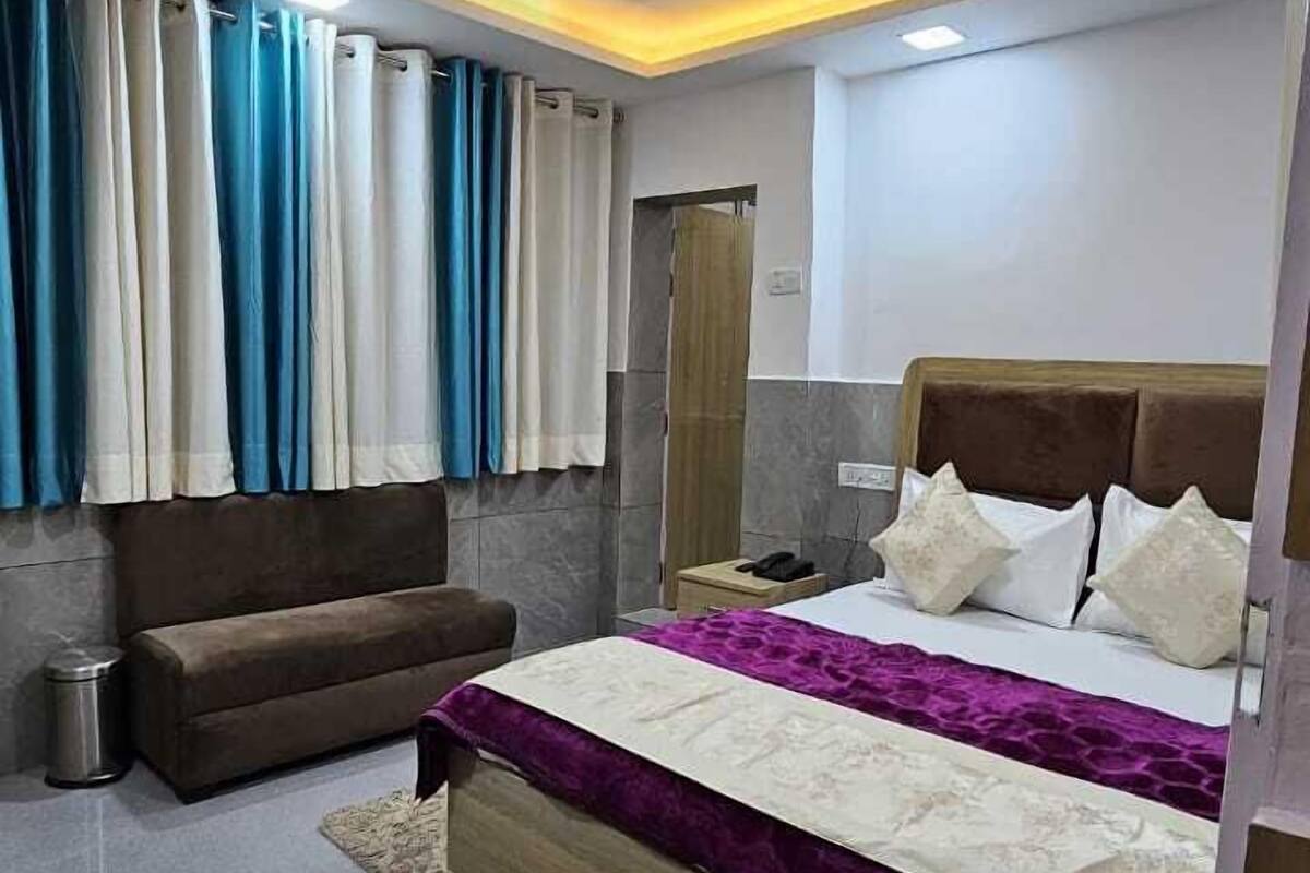 A modern bedroom with a bed, a sofa, a ceiling fan, and curtains.