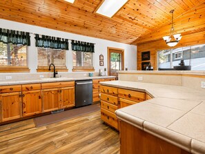 A kitchen with wooden cabinets, a dishwasher, and a large island.