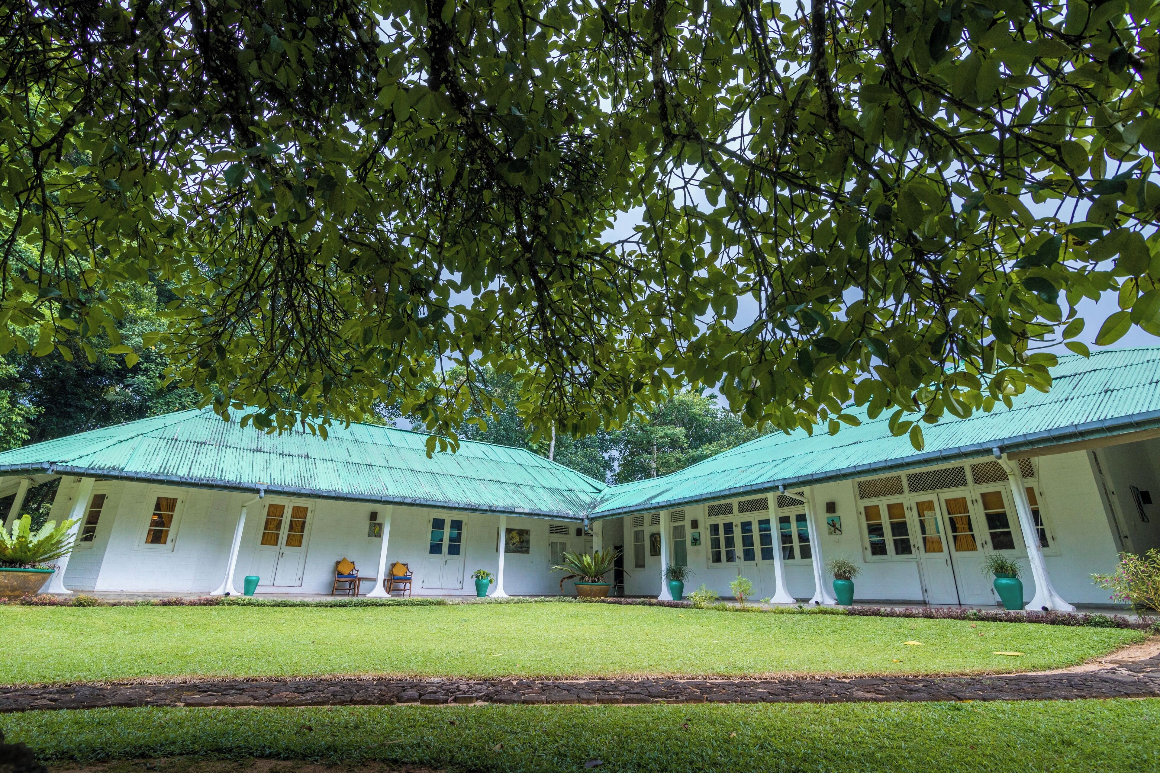 A two-story building with a green roof, white walls, and a covered porch area.