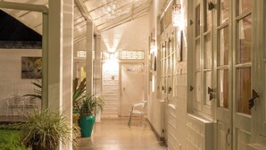 Un couloir avec un plafond, des plantes en pot et des portes.