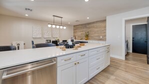 Een moderne keuken met een groot eiland, witte kasten en een houten accentmuur.