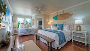 A bedroom with a bed, a bench, a surfboard, and a window with a view.