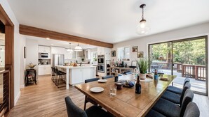Una cocina amplia con armarios blancos, una mesa de comedor de madera y un ventanal con vistas al exterior.