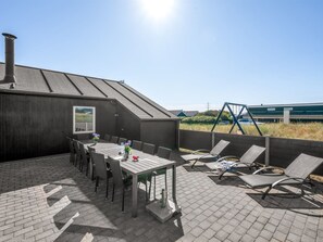 A patio with a table and chairs, a swing set, and a view of the sky.