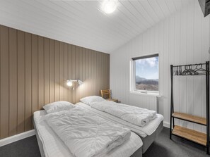 A bedroom with two beds, a window with a view, a radiator, and a bedside table. - "Agnes" - 900m from the sea by Interhome (Ringkøbing)