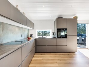 A modern kitchen with a large window, built-in appliances, and a minimalist design.
