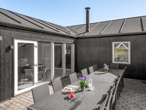 An outdoor patio with a long table, chairs, and a chimney.
