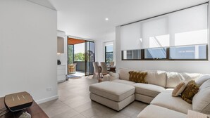 Ein modernes Wohnzimmer mit einem Ecksofa, einem Essbereich mit Stühlen und einer Küchenzeile mit Arbeitsplatte und Schränken.