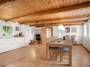 Una cocina amplia con piso de madera, un comedor con mesa y sillas, y un ventanal que proporciona luz natural.
