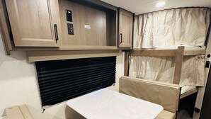 A compact RV interior with a kitchenette, a dining area, and a sleeping berth. - Cozy RV in Welcoming San Diego with WiFi, AC (San Diego)