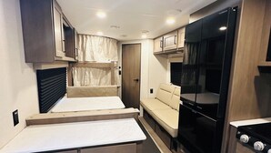 A compact kitchenette with a countertop, stove, and storage cabinets. - Cozy RV in Welcoming San Diego with WiFi, AC (San Diego)