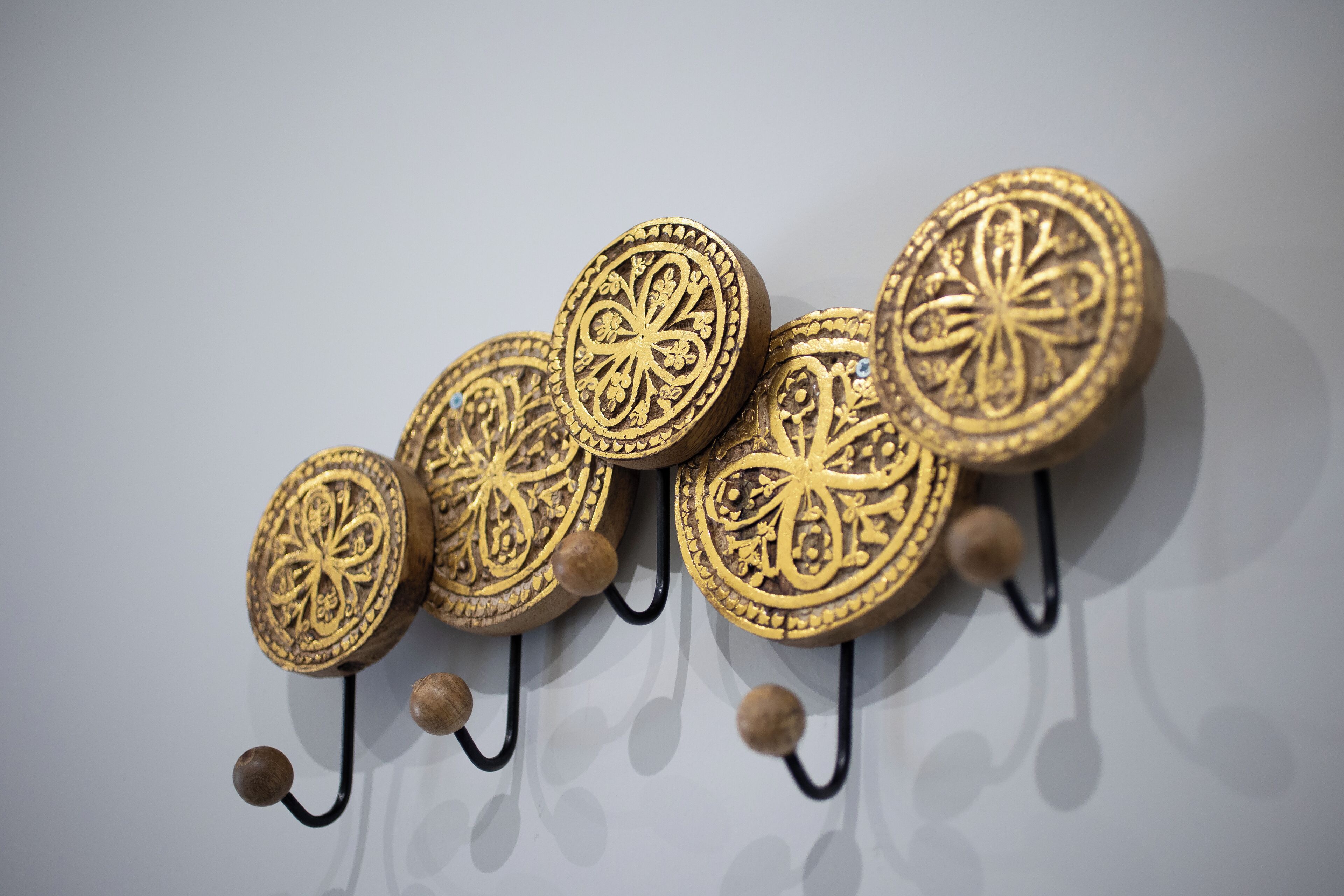 A wall-mounted hook with decorative, circular, gold-colored items.