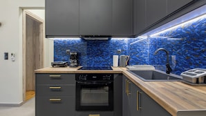 Una cocina moderna con armarios oscuros, encimera de madera y salpicadero de mosaico azul.