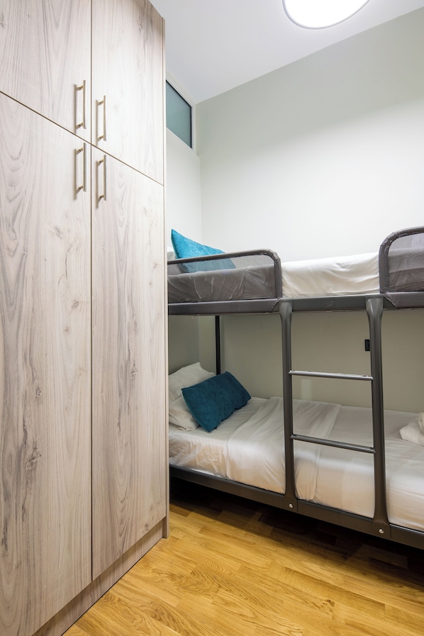Camera con letto a castello, un armadio in legno e una piccola finestra.