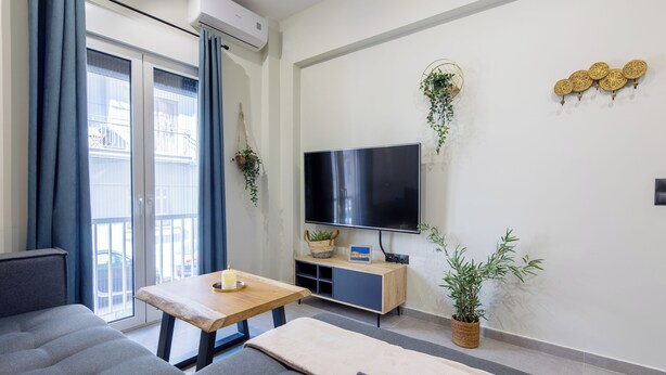 Una sala moderna con un sofá, una mesita de madera, un televisor y decoración en la pared.