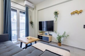 Un soggiorno moderno con un divano, un tavolino in legno, una TV e decorazioni a parete.