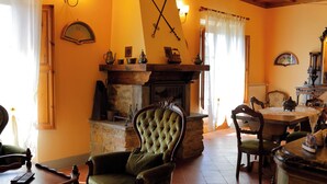 A traditional living room with a fireplace, a green armchair, and a dining table. - Agriturismo Villa Guarnaschelli (Scandicci)