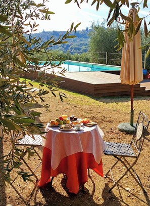 A table set outdoors with a pool in the background. - Agriturismo Villa Guarnaschelli (Scandicci)