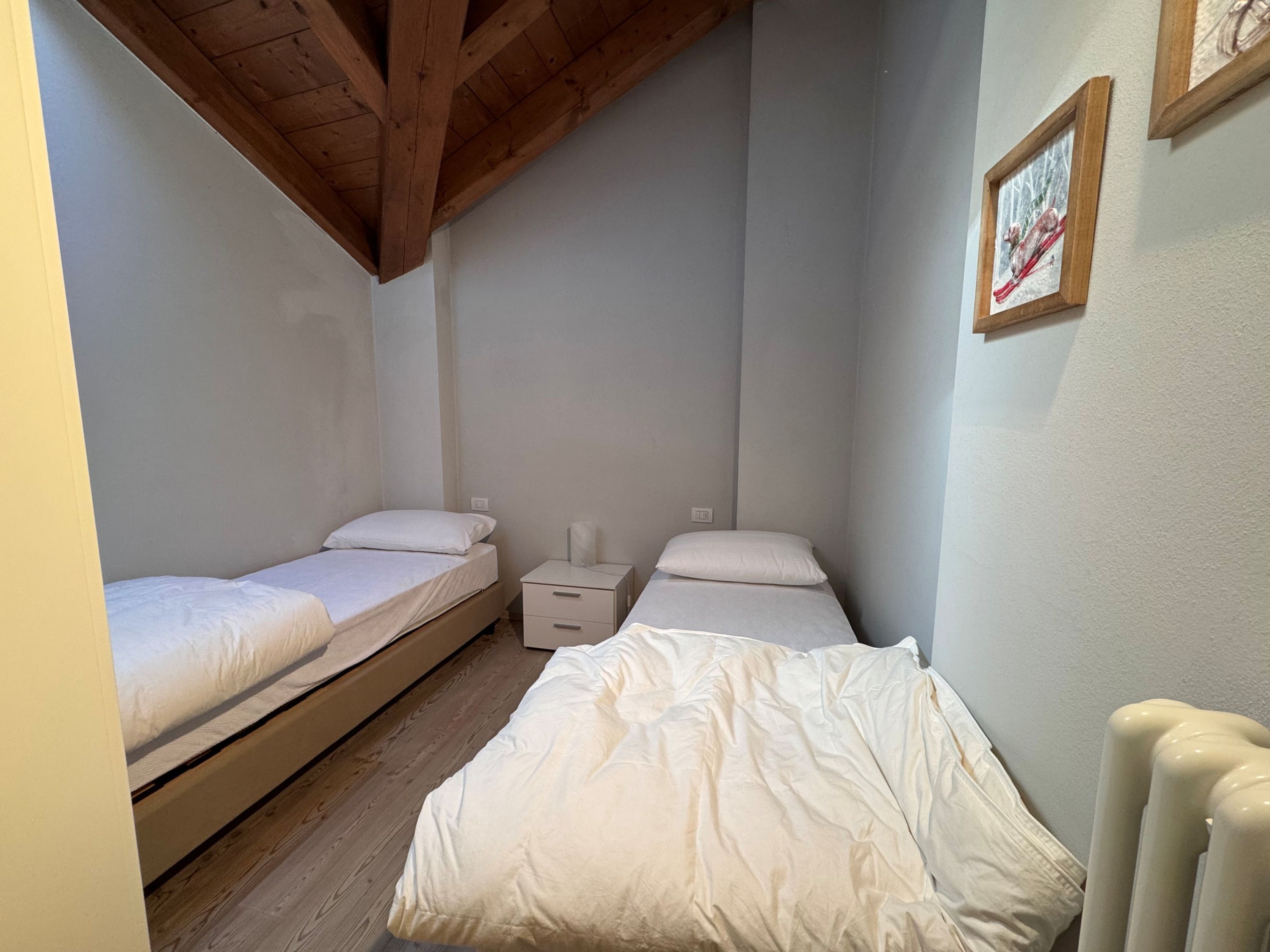 Une petite chambre confortable avec deux lits simples, une table de chevet et un radiateur.