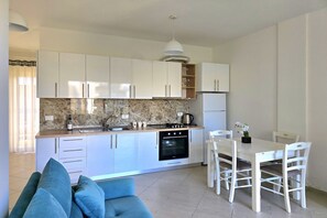 Enjoy cooking in this well-equipped kitchen with oven and sink, adjacent to a dining area with a table and chairs.