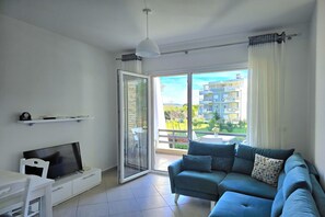 Relax in this stylish living room with a large flat-screen TV and sliding glass door leading to a balcony with a view.
