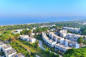 Stunning residential area with modern apartment buildings surrounded by lush greenery and a scenic coastline.