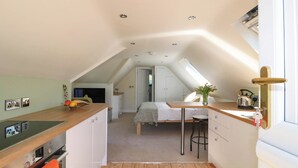 Eine kleine, moderne Küche mit Holzarbeitsplatte, einem eingebauten Ofen und einer Essecke mit Tisch und Stühlen.