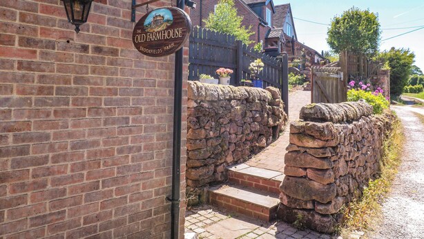 Ein Backsteinhaus mit einem Schild, auf dem 'The Old Farmhouse Brookfields Farm' steht.