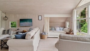 A cozy room with a large bed, a sofa, and a desk. There is a window with a view of greenery outside. - "Tekla" -  from the sea by Interhome (Rørvig)