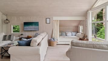 Une pièce confortable avec un grand lit, un canapé et un bureau. Une fenêtre offre une vue sur la verdure environnante.